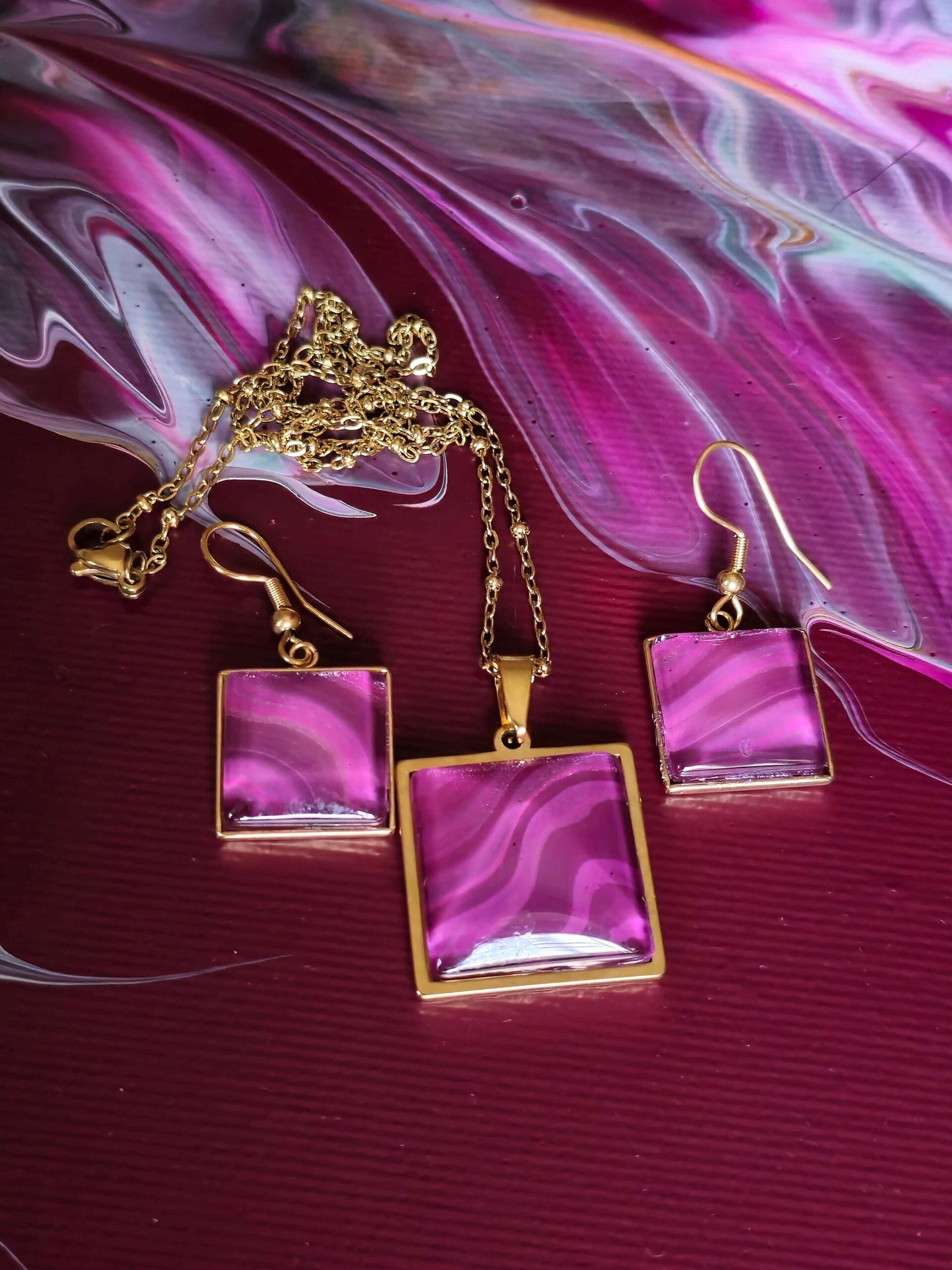gioielli artigianali fluid art - collana e orecchini in acciaio inossidabile con pendente quadrato placcato color oro cabochon quadrato color magenta e amaranto iridescenti