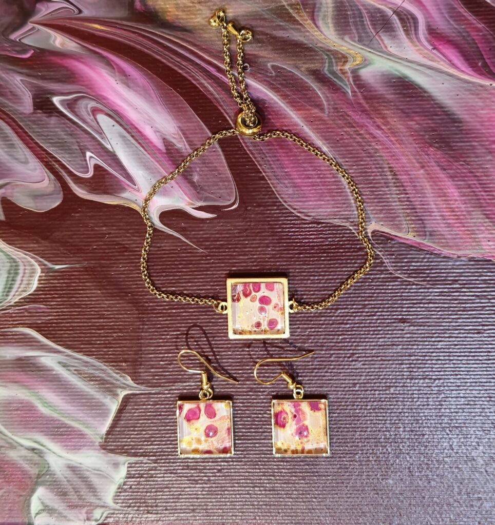 Gioielli artigianali set coordinato formato da bracciale e orecchini in acciaio inossidabile placcato color oro con cabochon in vetro quadrato e vernice acrilica fondo bianco effetto fiore magenta e oro