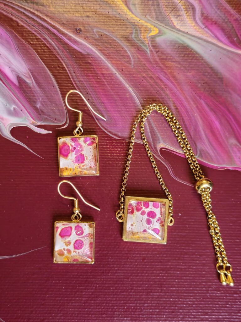 Gioielli artigianali set coordinato formato da bracciale e orecchini in acciaio inossidabile placcato color oro con cabochon in vetro quadrato e vernice acrilica fondo bianco effetto fiore magenta e oro