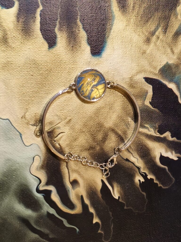 bracciale artigianale fluid art semi rigido in acciaio inossidabaile con cabochon rotondo in vetro e vernice acrilica oro e blu iridescenti