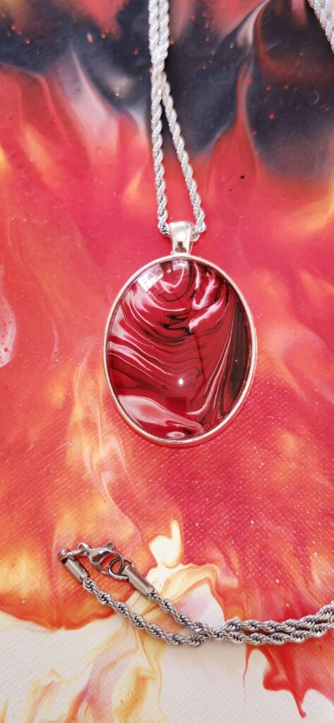 collana artigianale fluid art con catena 7acciaio inossidabile 70cm e pendente in lega ovale 30x40mm cabochon in vetro con vernice acrilica rossa fuoco nero,bianco. Autore AmarAnto Arte