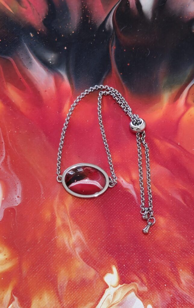 bracciale artigianale fluid art in acciaio inossidabile modello sali scendi con cabochon ovale 13x18 in vetro e vernice acrilica colore rosso nero e bianco. autore AmarAnto Arte