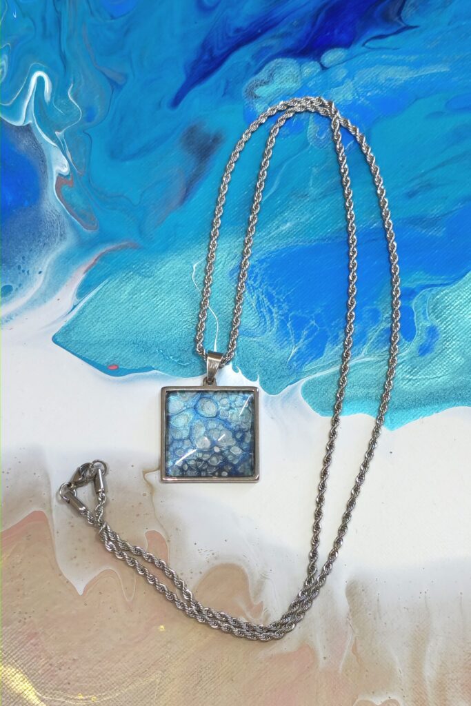 Bijoux artigianale fluid art - collana con ciondolo quadrato effetto mare color celeste azzurro iridescente turchese in acciaio inossidabile 25mm, color turchese, azzurro iridescenti effetto mare.autore AmarAnto Arte