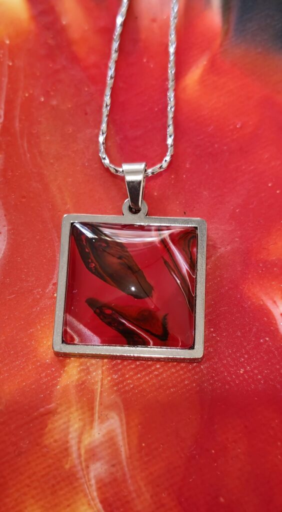 Bijoux fluid art. Particolare ciondolo quadrato cabochon 20 mm colore rosso, nero e bianco. autore AmarAnto Arte