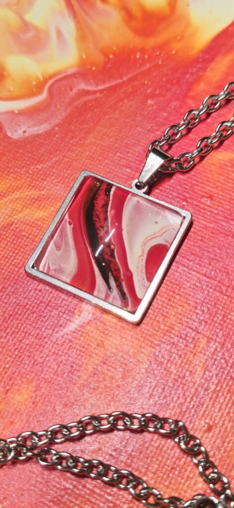 Particolare collana artigianale fluid art con catena 70cm e pendente quadrato 25mm in acciaio inossidabili cabochon in vetro con vernice acrilica rossa fuoco nero,bianco. Autore AmarAnto Arte