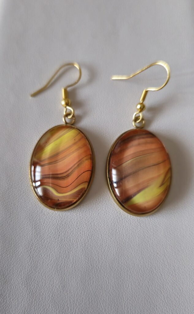 orecchini artigianali fluid art in acciaio inossidabile color oro cabochon ovale in vetro 13x18 vernice acrilica color giallo arancio, marrone, bronzo, oro. autore AmarAnto Arte