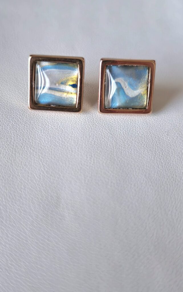 orecchini artigianali fluid art quadrati in acciaio inossidabile color oro rosa cabochon vetro 10mm vernice acrilica colore celeste, oro e bianco. autore AmarAnto Arte