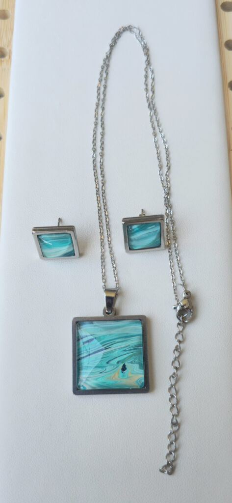 collana artigianale fluid art con catena 45 cm in acciaio inossidabile pendente quadrato in acciaio inossidabile 20mm cabochon in vetro con vernice acrilica turchese, blu, oro. autore AmarAnto Arte