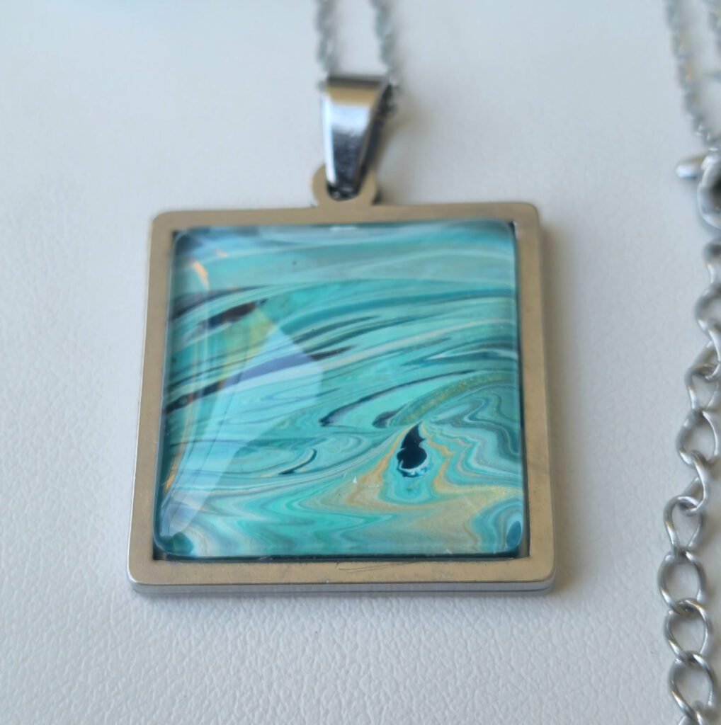 collana artigianale fluid art con catena 45 cm in acciaio inossidabile pendente quadrato in acciaio inossidabile 20mm cabochon in vetro con vernice acrilica turchese, blu, oro. autore AmarAnto Arte
