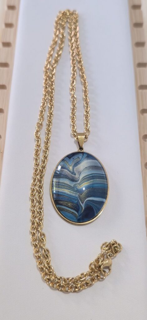 collana artigianale fluid art in acciaio inossidabile color oro, lunghezza 70 cm con ciondolo ovale 30x40mm color blu, celeste, turchese oro, rame iridescenti.Autore AmarAnto Arte