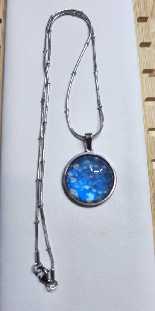 collana con pendente rotondo 20mm in acciaio inossidabile vernice acrilica effetto mare color blu e argento iridescenti. autore AmarAnto Arte