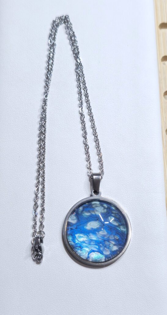 collana con pendente rotondo 20mm in acciaio inossidabile vernice acrilica effetto mare color blu e argento iridescenti. autore AmarAnto Arte