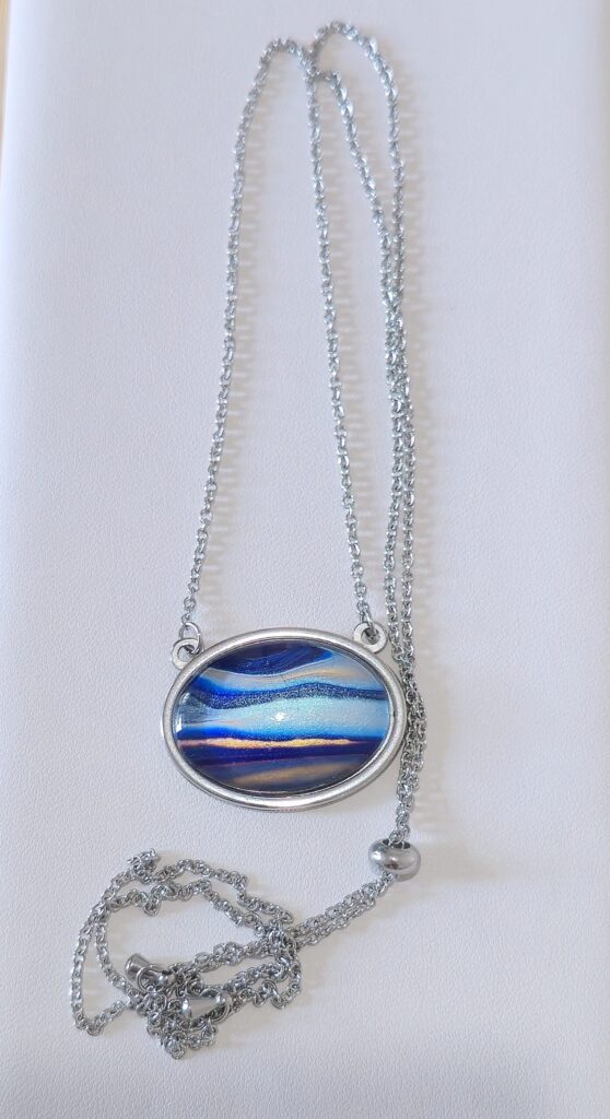 collana fluid art artigianale con catena saliscendi e pendente ovale 18x25 in acciaio inossidabile vernice acrilica color blu, celeste, turchese, arancione iridescenti.Autore AmarAnto Arte