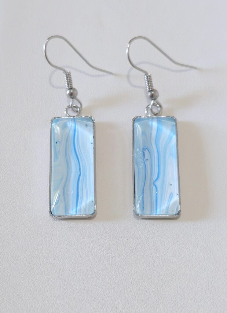 orecchini artigianali fluid art con pendente rettangolo in acciaio inossidabile vernice acrilica colore celeste, azzurro. autore AmarAnto Arte