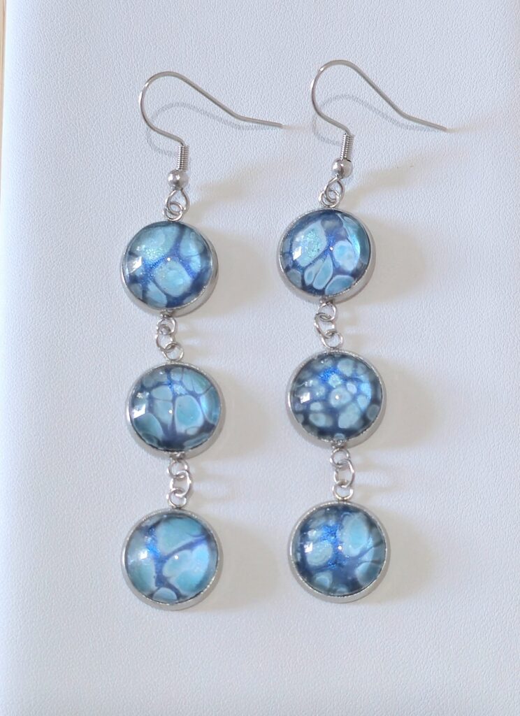 orecchini artigianali fluid art pendenti in acciaio inossidabile con tre cabochon rotondi vetro 12mm vernice acrilica colore celeste, blu, argento iridescenti. autore AmarAnto Arte