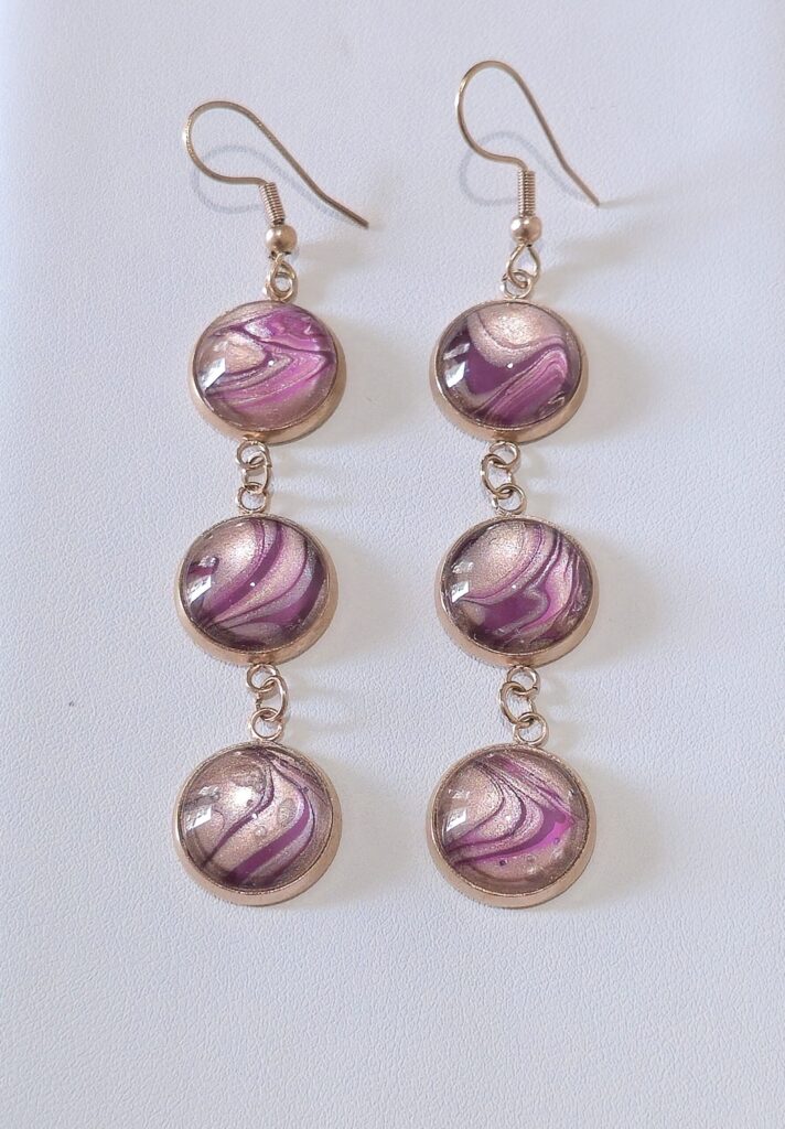orecchini artigianali fluid art pendenti in acciaio inossidabile golden rose con tre cabochon rotondi vetro 12mm vernice acrilica colore amaranto, rosa perlato. autore AmarAnto Arte