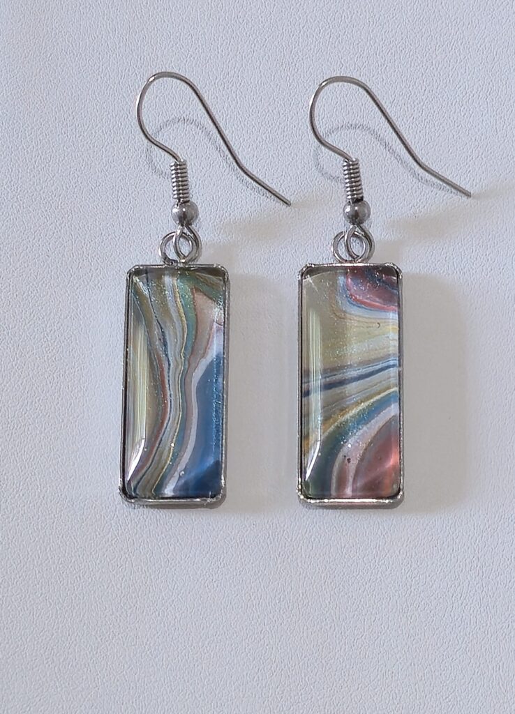 orecchini artigianali fluid art con pendente rettangolo in acciaio inossidabile vernice acrilica colore multicolor celeste oro beige rosa. autore AmarAnto Arte